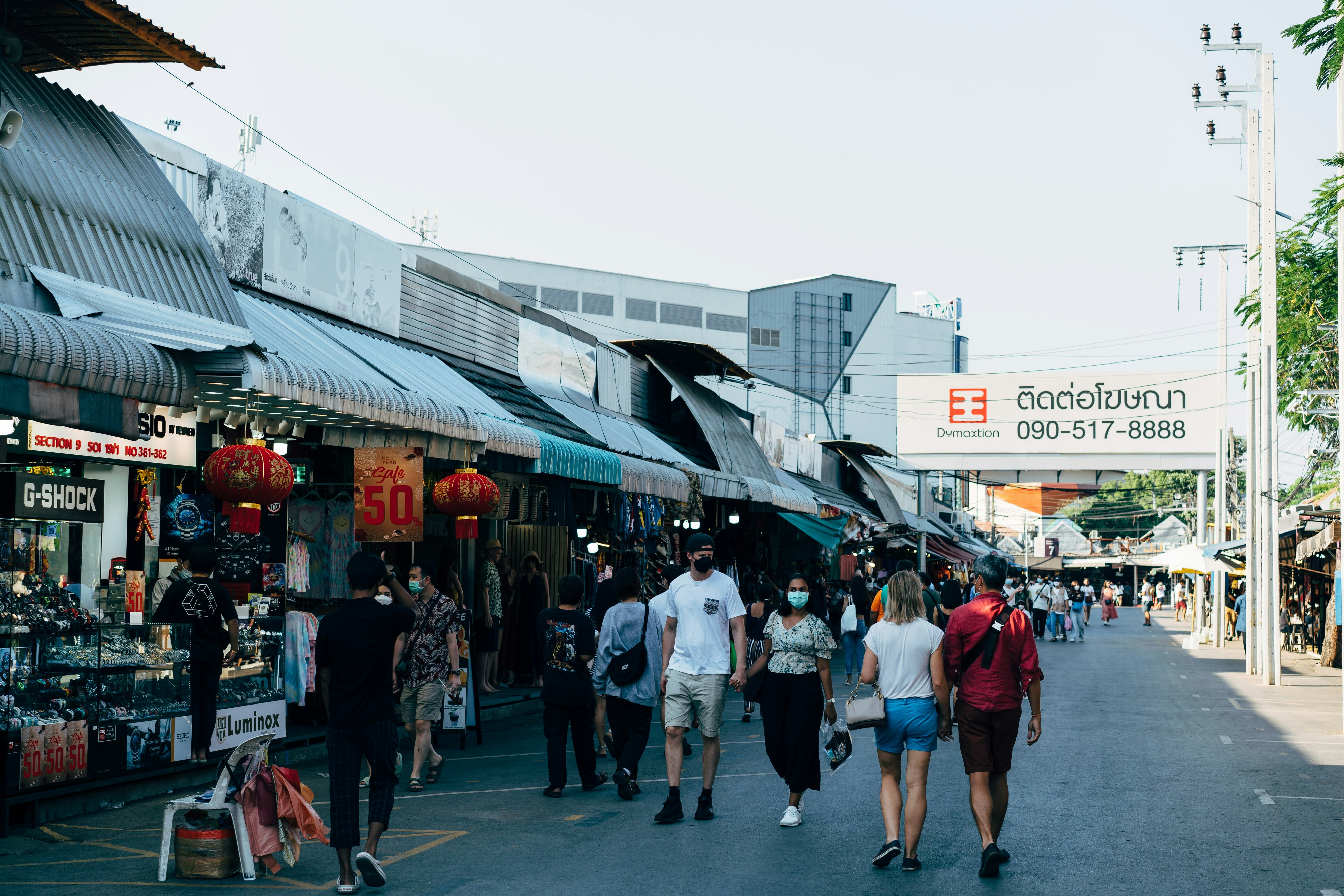 a group of people walking down a street next to shops